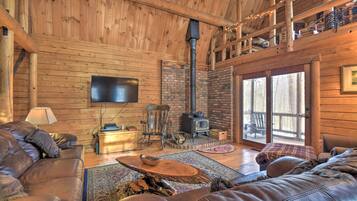 A cozy cabin interior with a wooden interior, a fireplace, a television, and a comfortable seating area.