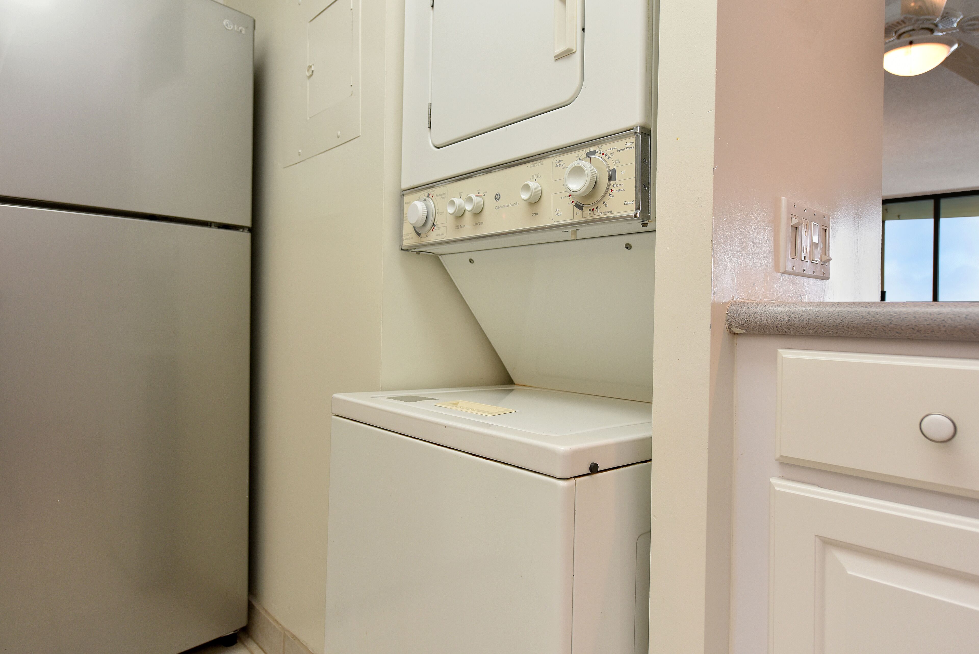A compact laundry room with a washing machine and dryer, a countertop, and a light switch.