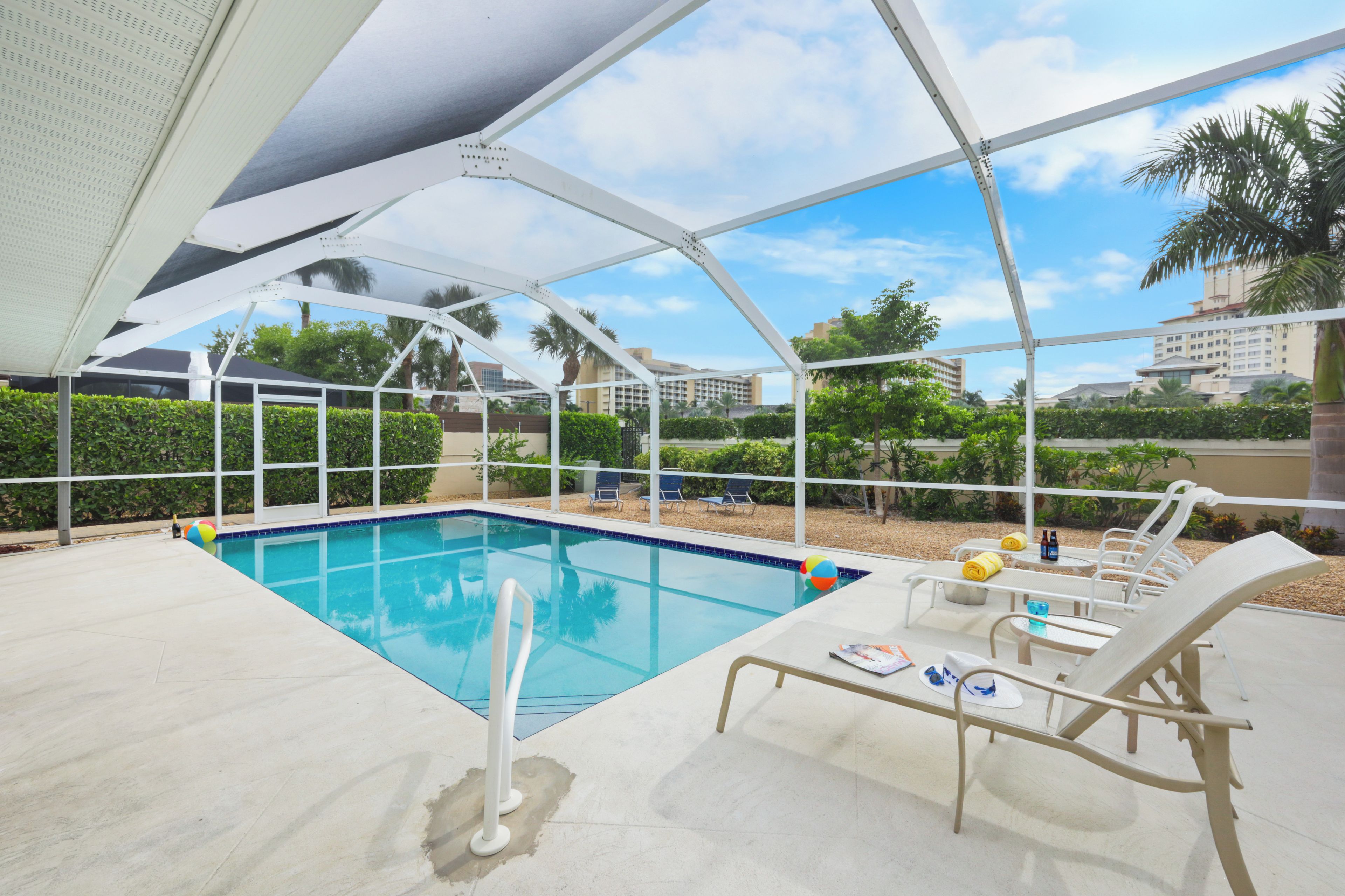 A covered pool area with lounge chairs and a poolside table.