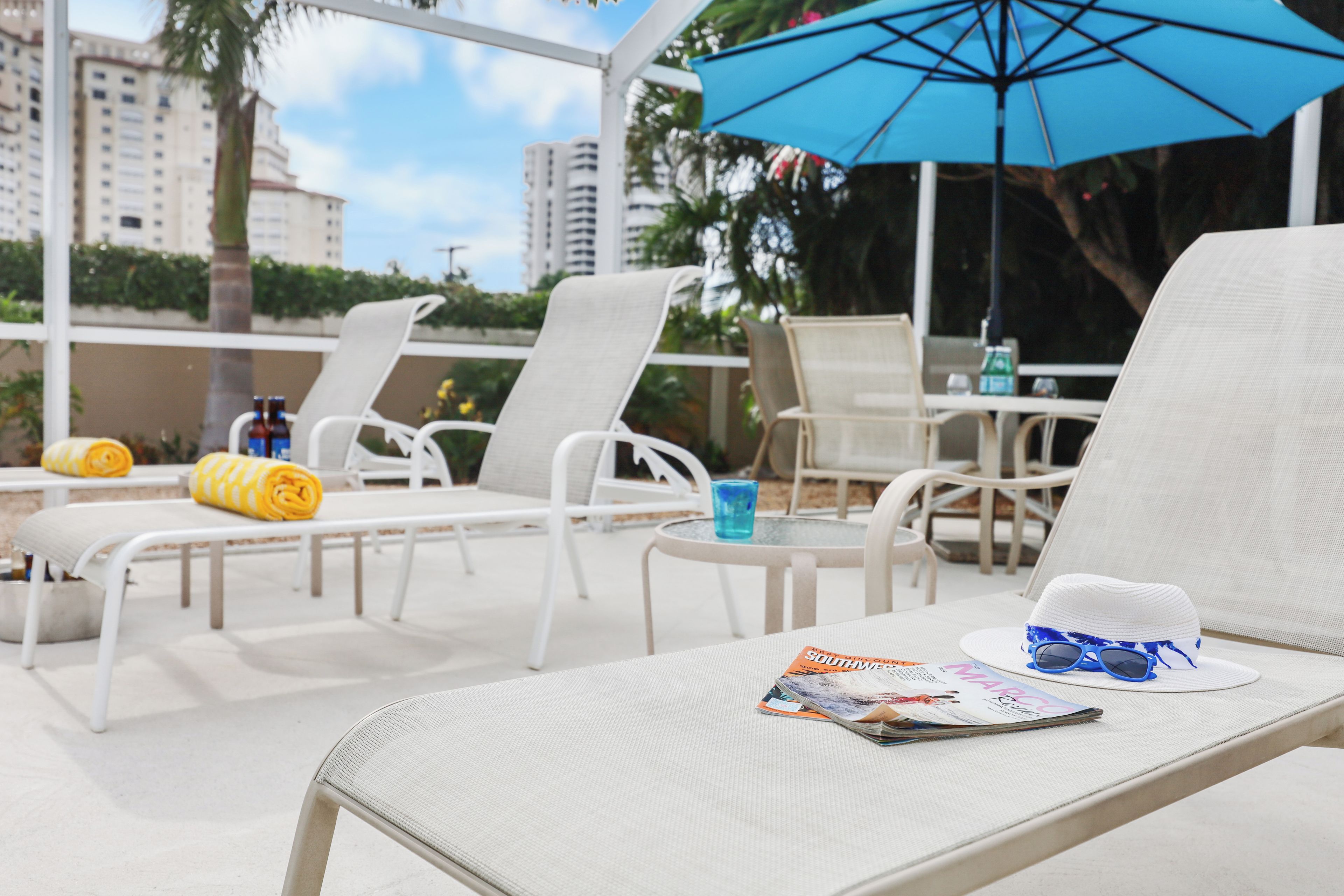 A poolside area with lounge chairs, a table, and a magazine.