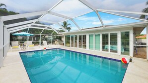 Une piscine couverte avec des parois en verre transparent, des chaises longues et des parasols.