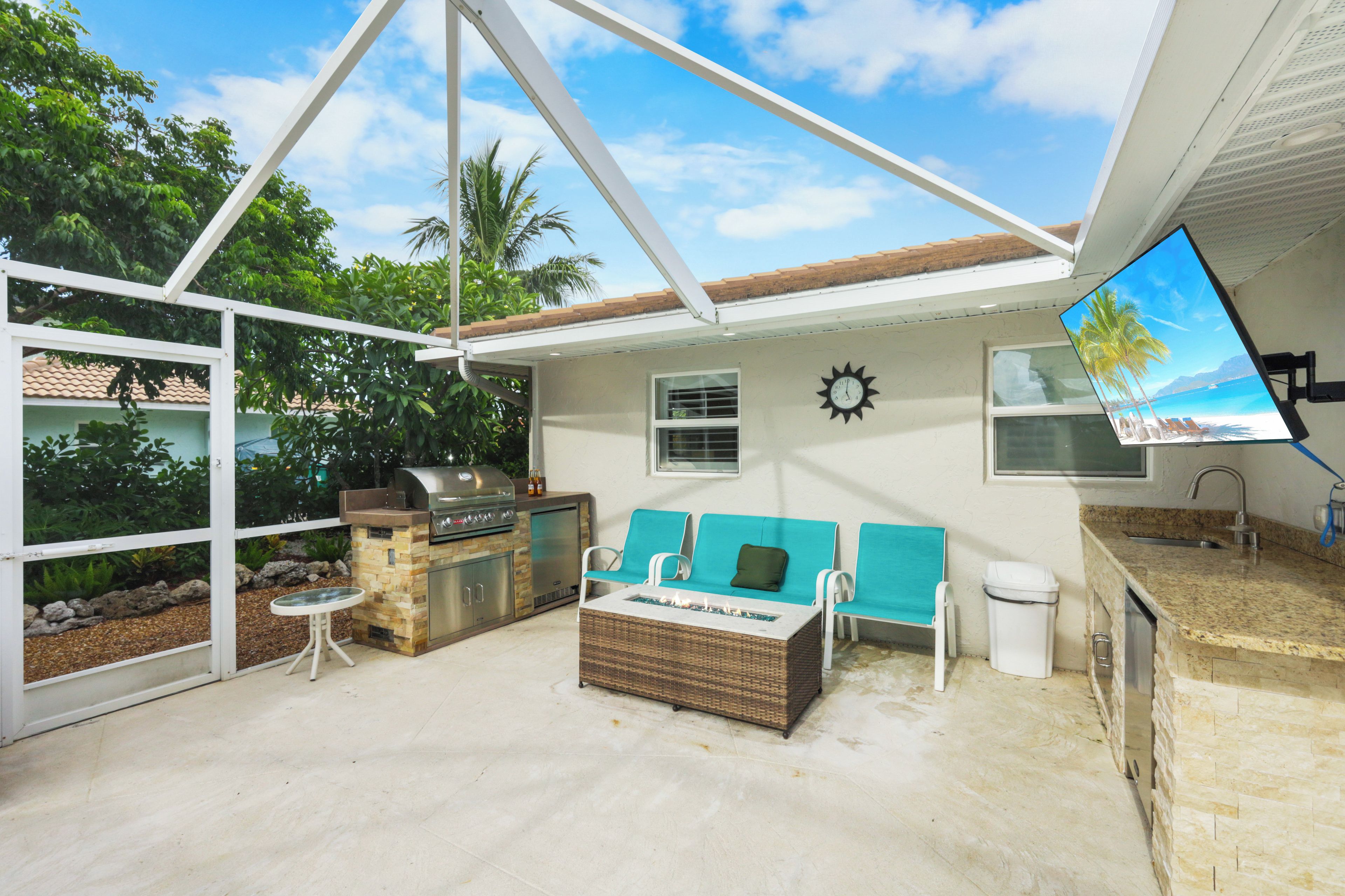 An outdoor patio with a grill, seating area, and a view of the beach.