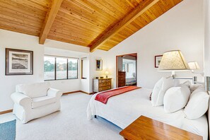 Cozy retreat with a large bed, armchair, and sofa, offering a view of the outdoors.