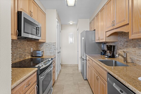 A kitchen with wooden cabinets, a microwave, a toaster, a refrigerator, and a dishwasher.