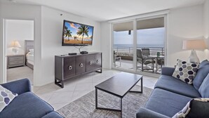 A modern living room with a television, sofa, and coffee table. - Gated Beachfront Condo | Nice Views, Pools & Ggym (Marco Island)