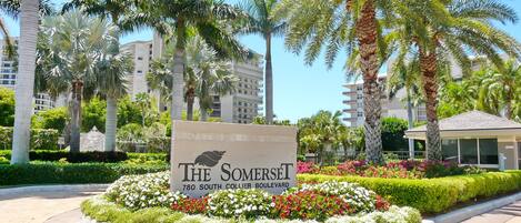 A sign for The Somerset at 780 South Collier Boulevard, surrounded by landscaped gardens and palm trees.