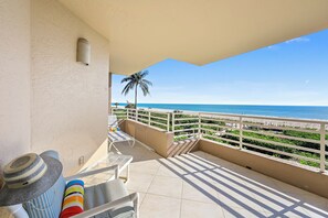 Ein Balkon mit Blick auf den Strand, eine Palme und ein Fliesenboden.