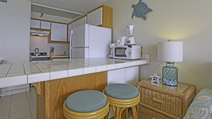Een kleine keuken met witte apparaten, een houten aanrecht en twee barkrukken.