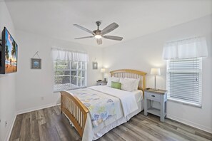A bedroom with a bed, bedside tables, a ceiling fan, and windows with blinds. - Inviting and Quiet Home | Pool & Steps to Beach (Marco Island)