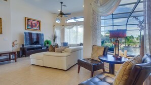 A spacious living room with a sofa, a coffee table, and a television. - Upscale Marco Island Villa w/ Outdoor Bar + Pool! (Marco Island)