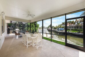A spacious room with a large window overlooking a marina and greenery.