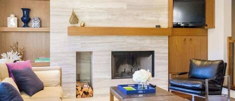 A modern living room with a fireplace, a television, a sofa, and a coffee table.
