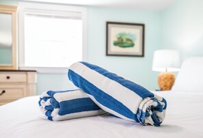 A neatly made bed with a blue and white striped towel.