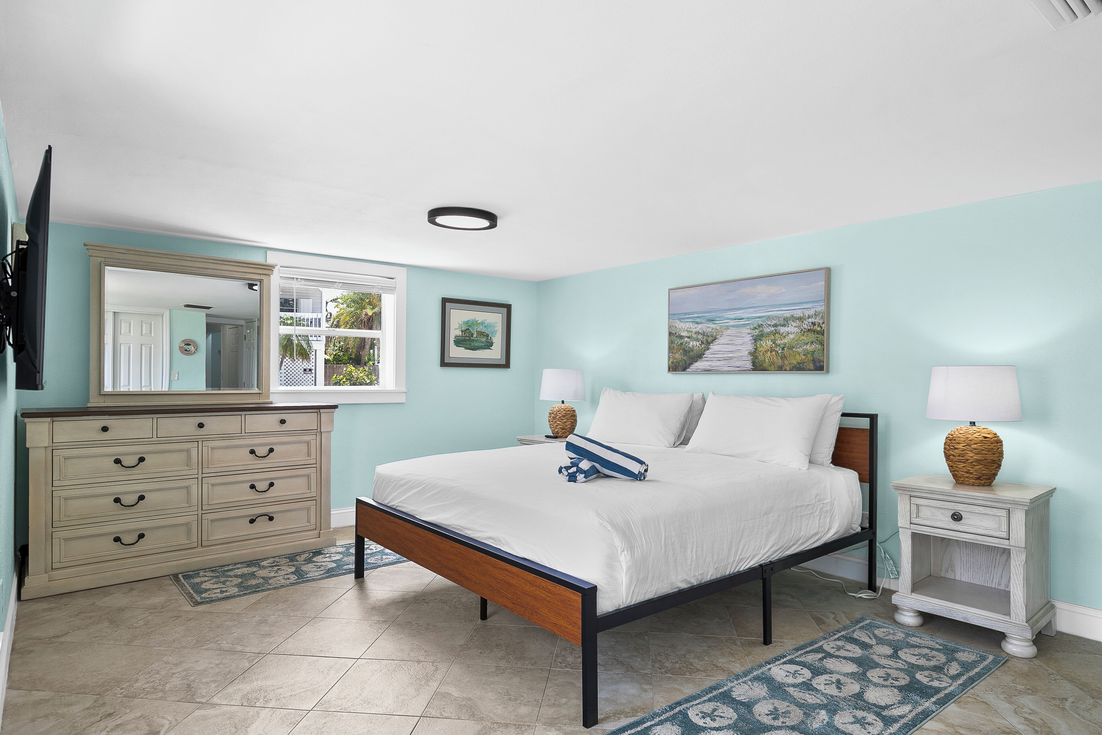 A bedroom with a bed, nightstands, a dresser, and a mirror.