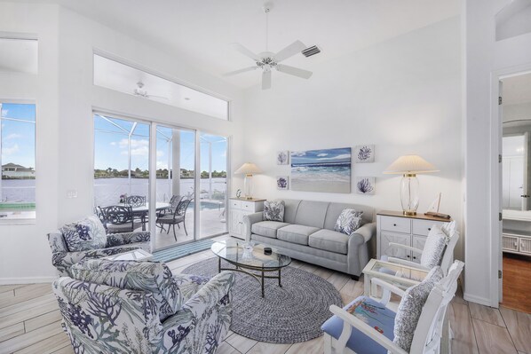 A spacious living area with a large window, a ceiling fan, and a view of the outdoors.