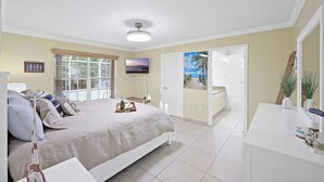 A bedroom with a bed, bedside table, and a view of the outside. - Pet-friendly Waterfront | Pool & Steps to Beach (Marco Island)