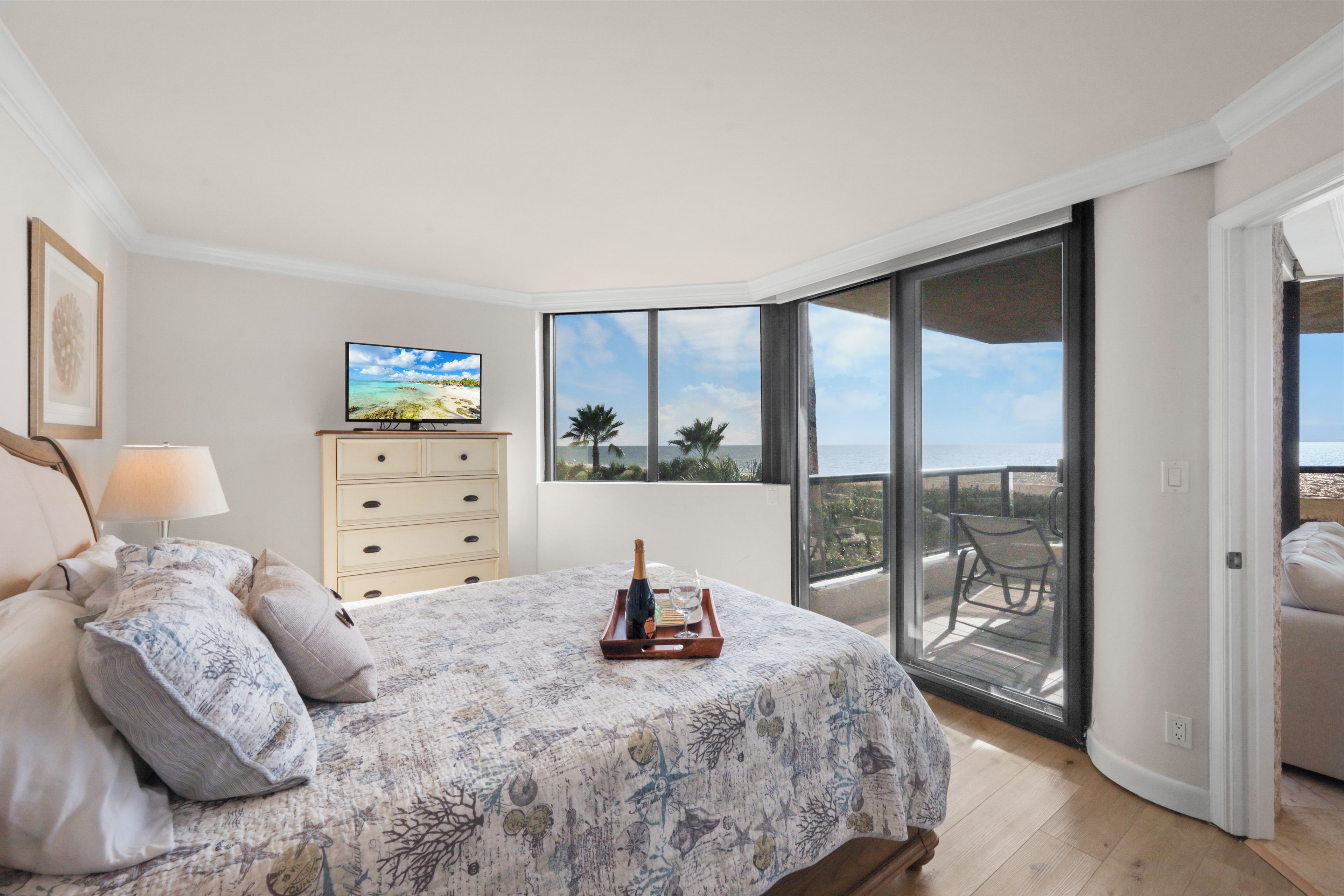 A bedroom with a bed, a TV, a nightstand, and a view of the outdoors through a sliding glass door.
