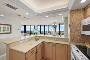 A modern kitchen with a large island, built-in appliances, and a view to the outside. - Stylish Beachfront Condo | Spa/Pool & Ocean Views (Marco Island)
