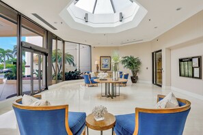 A spacious lobby with a high ceiling, a central round table, and seating arrangements. - Stylish Beachfront Condo | Spa/Pool & Ocean Views (Marco Island)