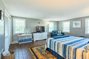 A bedroom with a large bed, a dresser, a TV, and a window.