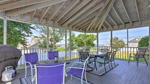 Un patio techado al aire libre con mesa y sillas, una parrilla y vistas al vecindario.