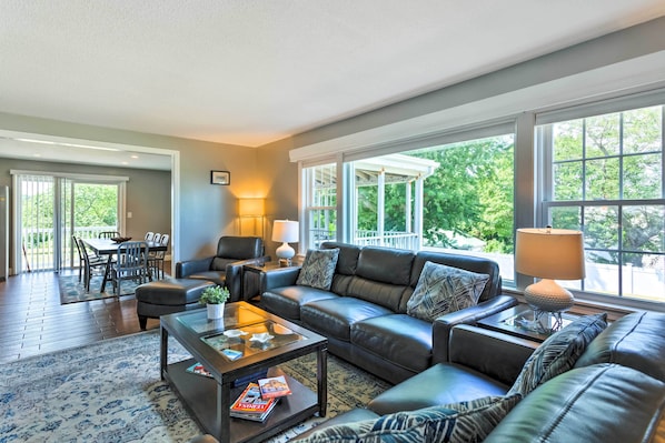 A spacious living room with a leather sofa, a glass coffee table, and a dining area with a table and chairs.