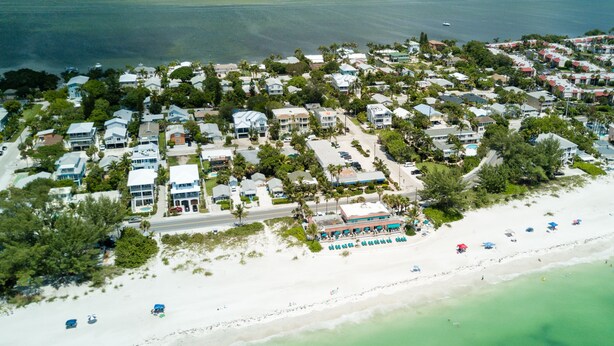 An aerial view of a coastal residential area with houses, a beach, and a resort with multiple rooms and a pool. - Sail Away Cottage · 170 Steps · Pool · 1920's Cottage (Bradenton Beach)