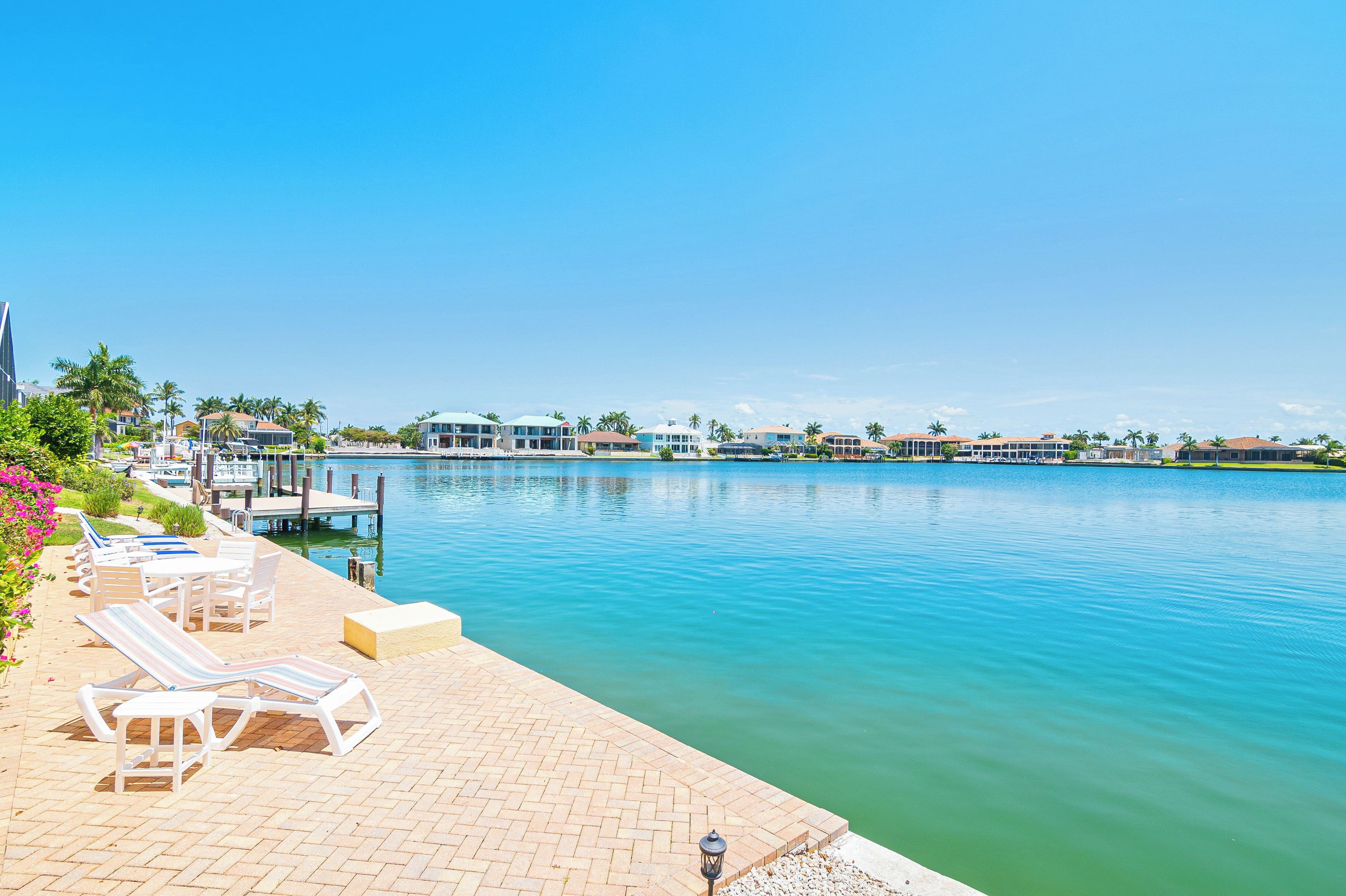 Hotel aan het water met een steiger, lounge stoelen en helder uitzicht op het water.