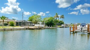 Un puerto deportivo con barcos amarrados, cielo despejado y edificios residenciales al fondo.