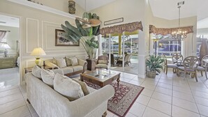 Un salón espacioso con un sofá grande, una mesa de centro y una zona de comedor con sillas y una mesa.