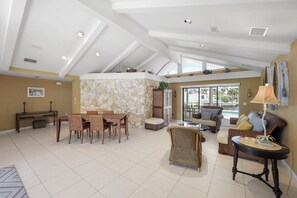 A spacious living area with a dining table, wicker furniture, and a view of the outdoors. - Boater’s Paradise | Unmatched Water Views (Marco Island)