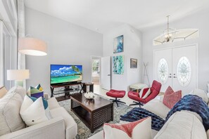 Un salon moderne doté d’un téléviseur à écran plat, de sièges confortables et d’éléments décoratifs.