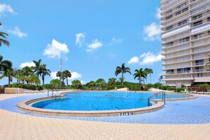 Une piscine d’un diamètre de 2,21 mètres, entourée de palmiers et avec un bâtiment d’hôtel en arrière-plan.