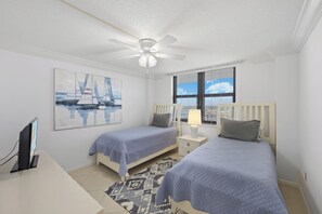 A bedroom with two beds, a ceiling fan, a desk with a computer, and a window with blinds. - Eye-Catching Beachfront Condo | Pool & Nice Views (Marco Island)