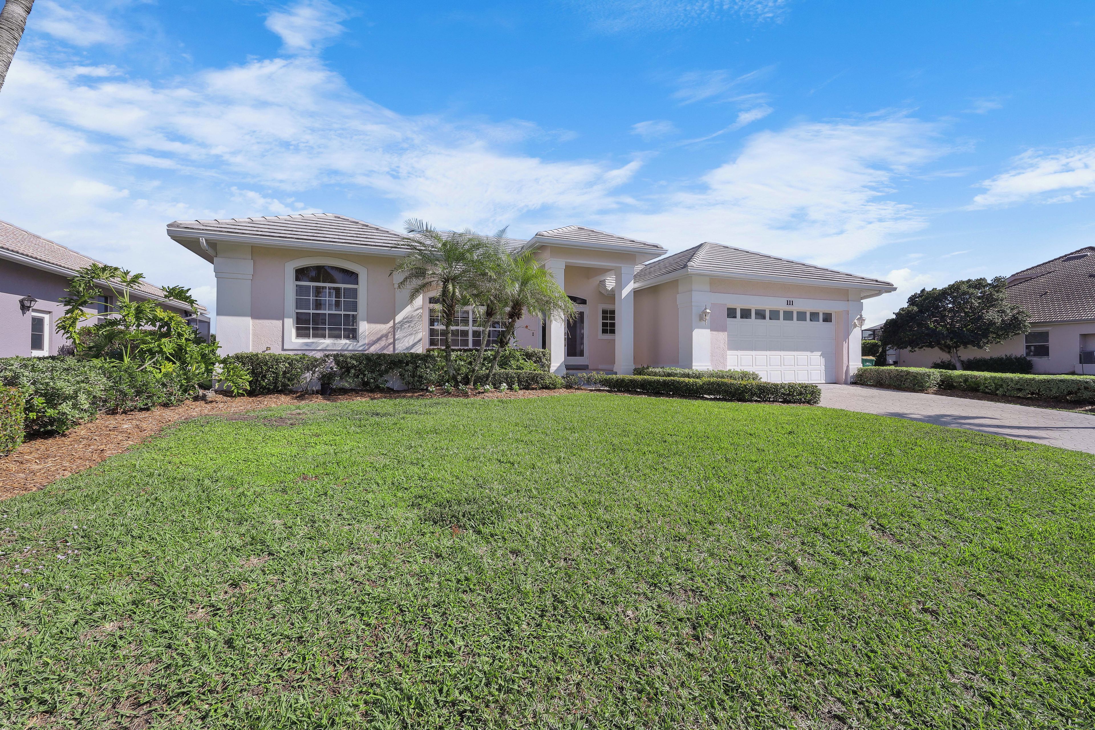 A residential house with a well-maintained lawn, a driveway, and a clear blue sky.