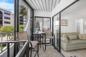 A balcony with a sofa, chairs, and a table with drinks.