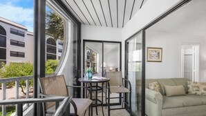 Un balcón con sofá, sillas y una mesa con bebidas.