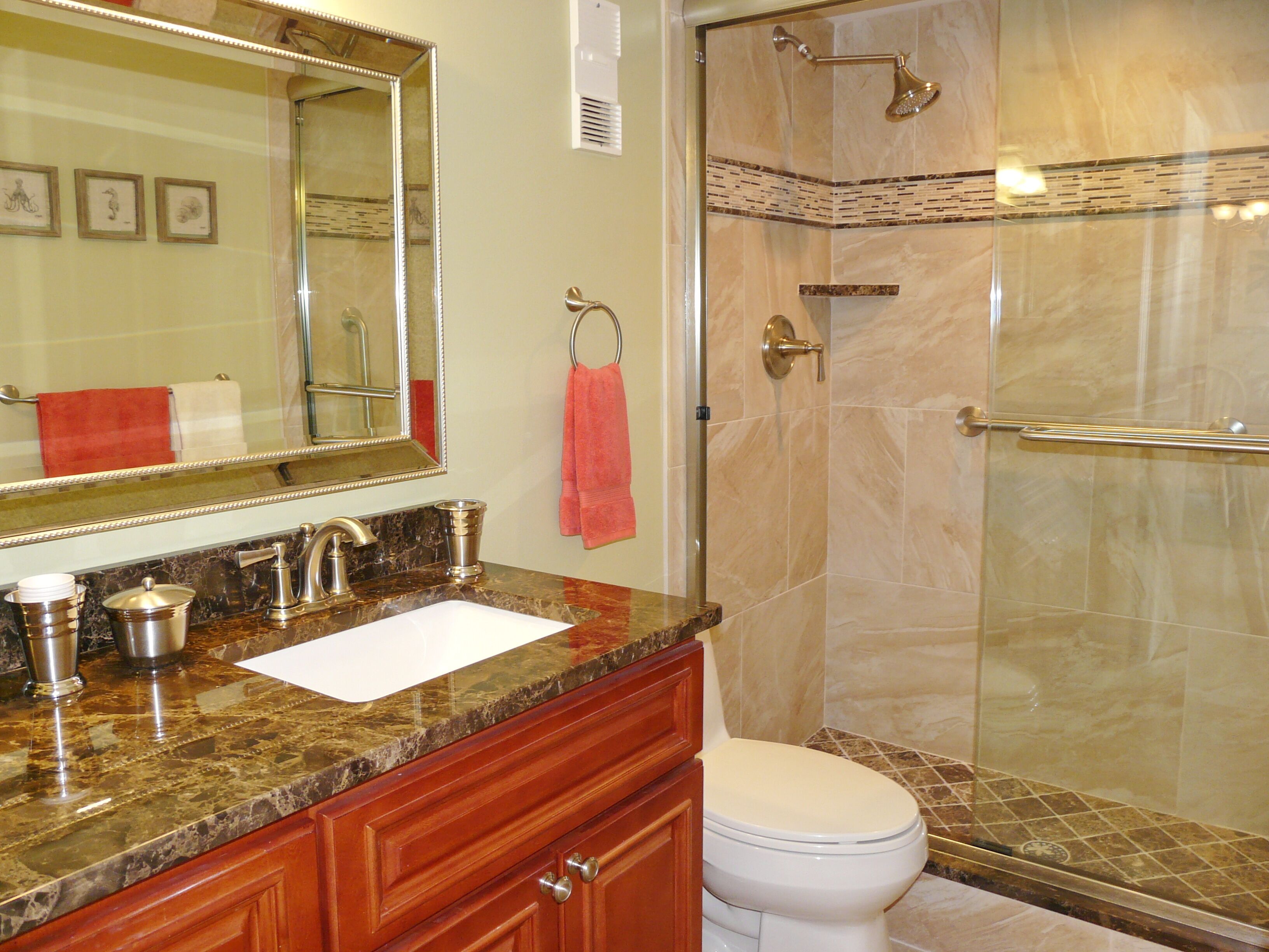 A bathroom with a marble vanity, a toilet, a shower with a glass door, and a large mirror.