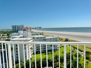 A beachfront hotel with multiple buildings, a beach view, and a clear sky.