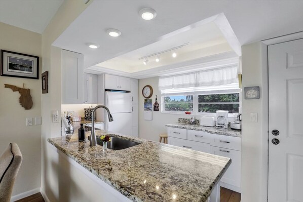 A modern kitchen with granite countertops, white cabinetry, and a built-in oven.