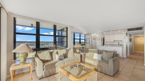 Amplia sala de estar con ventanas grandes, una cocina y un comedor.