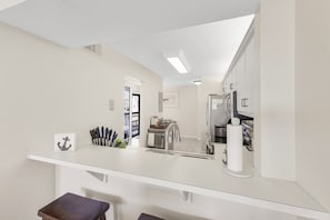 Une cuisine moderne avec des meubles blancs, un évier en acier inoxydable et un plan de travail agrémenté d’un range-couteaux et d’un porte-essuie-tout.