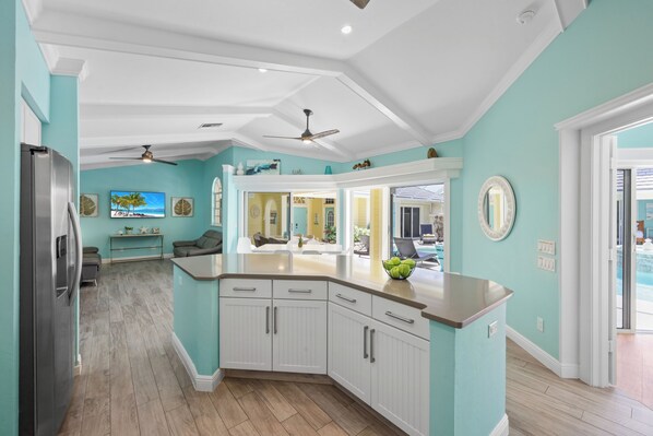 A modern kitchen with white cabinetry, a granite countertop, and a ceiling fan.