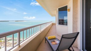 Un balcón con vistas al mar, una silla y una mesa con una revista.