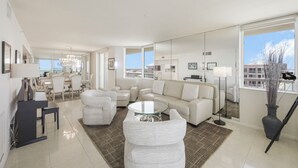 Una sala de estar moderna con un sofá, sillones, una mesa de centro y un comedor con sillas y una mesa.