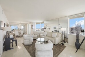 Un salon moderne comprenant un canapé, des fauteuils, une table basse et un coin repas avec des chaises et une table.
