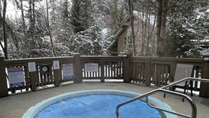 A swimming pool with a wooden deck, surrounded by trees and a building in the background. - Cozy Retreat in The Woods, Hot Tub & Free Parking (Whistler)