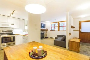 Una cocina moderna con electrodomésticos integrados, un comedor con mesa de madera y una sala de estar acogedora con chimenea.