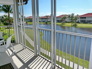 A balcony with a view of a water body and a building with a red roof.