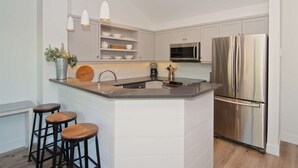 Una cocina moderna con una isla central, electrodomésticos de acero inoxidable y taburetes de bar.